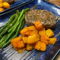 filet mignon and roasted vegetables on a blue plate