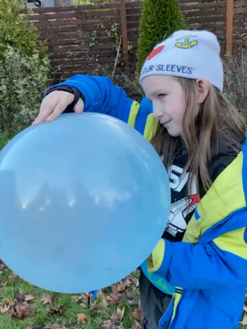 boy in hat and blue coat with super wubble balloon