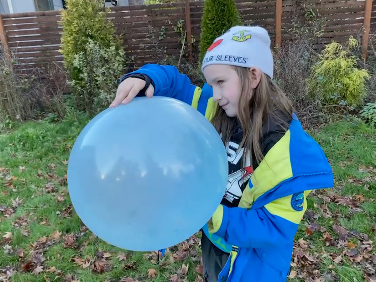 boy in hat and blue coat with super wubble balloon