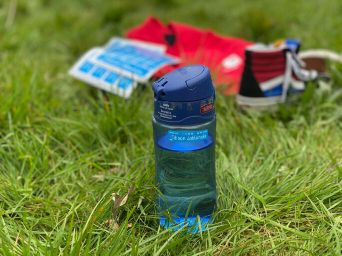 blue water bottle on grass with kids clothing in background