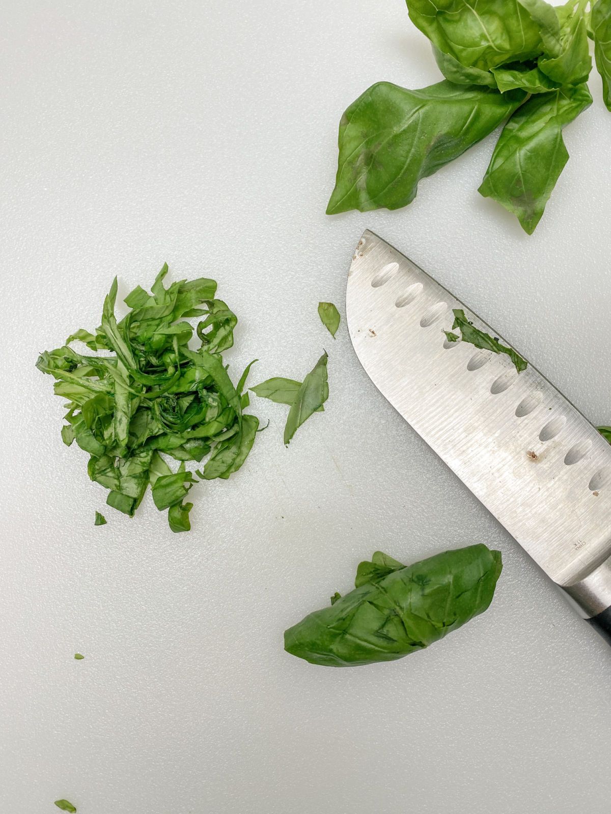 chiffonade basil on cutting board with knife