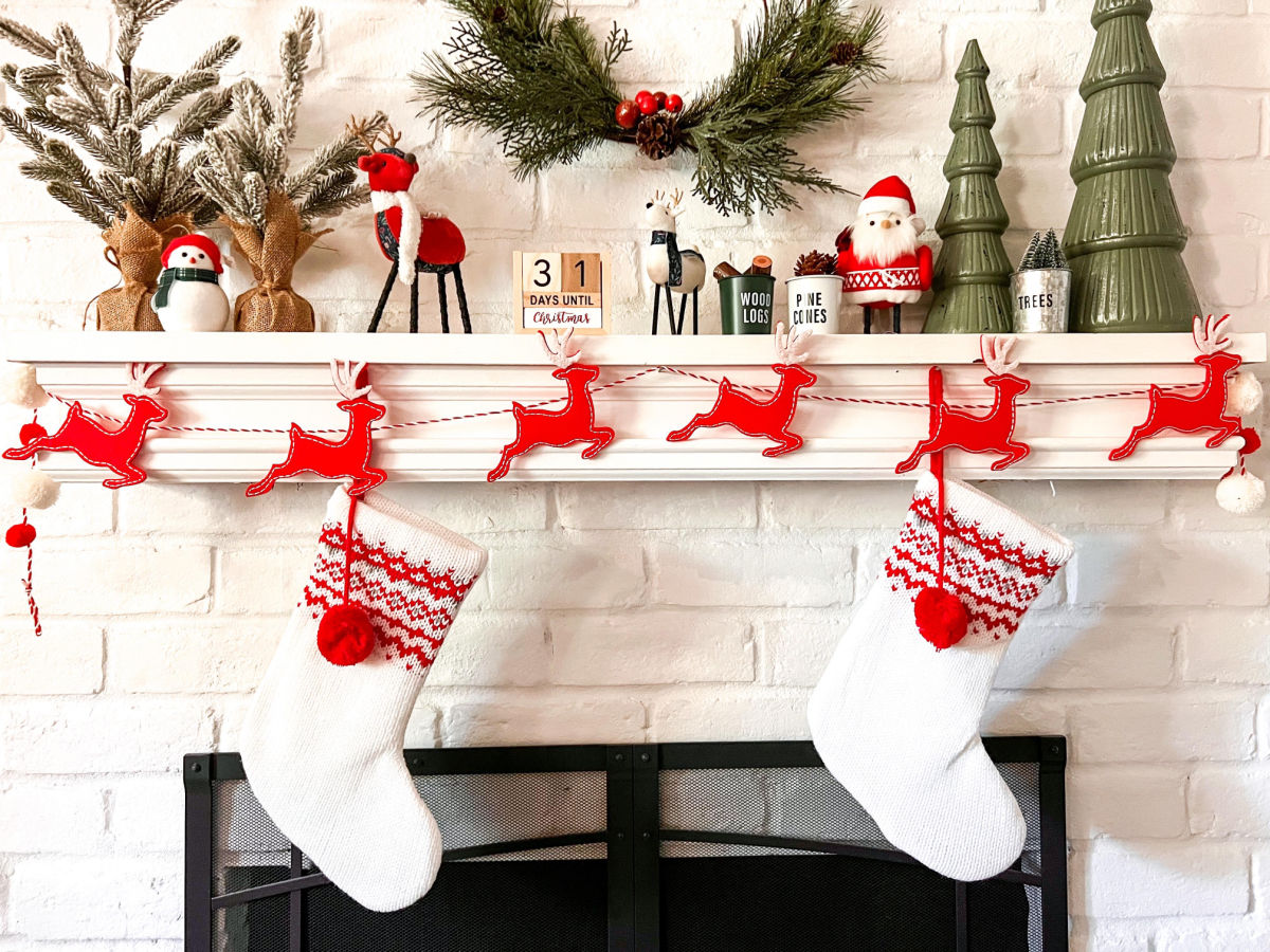white and red stockings hung on a white brick fireplace with holiday decor
