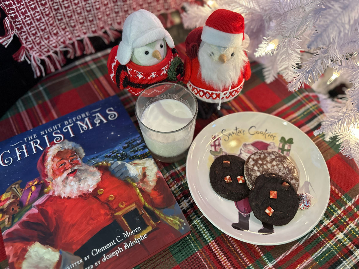 night before christmas book with milk and cookies and decorative birds on a red plaid table cloth
